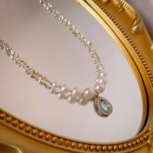 Detail of double-layer pearl necklace with blue teardrop zircon on vintage mirror