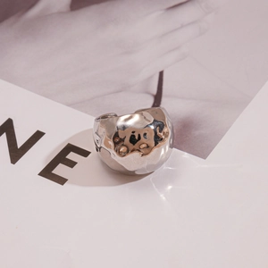 Détail d'une bague large argentée avec texture martelée sur une carte décorative