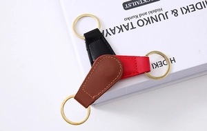 Detail of leather keychains in red, black, and brown with gold metallic rings