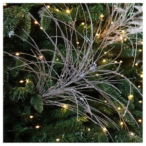 Close-up of silver glitter branch ornaments sparkling on a green Christmas tree