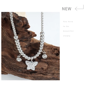 Close-up of a silver butterfly pendant necklace with sparkling crystals on natural wood