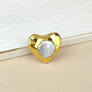 Detail of heart-shaped gold jewelry with a central natural pearl inlay and polished finish