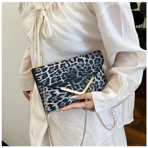 Detail of leopard print envelope bag featuring a gold V-shaped metal buckle and chain