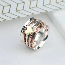 Detail van de meerlaagse roterende ring in driekleurig metaal met gouden hartelement