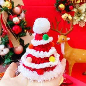 Close-up of handmade knitted Christmas tree hat with colorful pom-poms for pets
