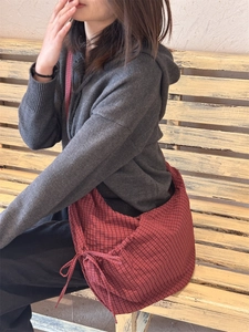 Detailed shot of red checkered nylon hobo bag with adjustable strap and bow decoration