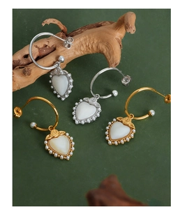 Detail of heart shell earrings with mini pearls and rose design on a vintage wooden prop