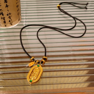 Detail of gold oval pendant with deity relief, green gemstones and Na Fu hanging tag