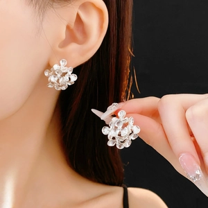 Close-up of elegant silver flower cluster earrings worn on ear with polished finish