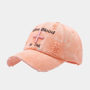 Macro detail of distressed washed cotton baseball cap with embroidered cross and text