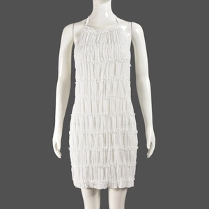 Detail of white halter dress featuring layered ruffles and textured pleated fabric design