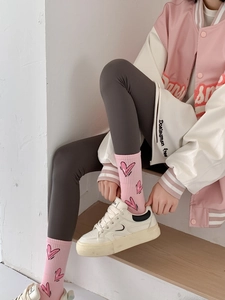 Close-up of pink crew socks with heart patterns worn with gray leggings and sneakers