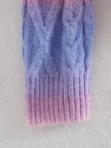 Macro detail of tie-dye knit sweater featuring pink purple gradient and cable patterns