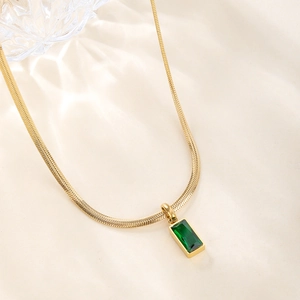 Detailed close-up of emerald square pendant on gold snake chain necklace for women