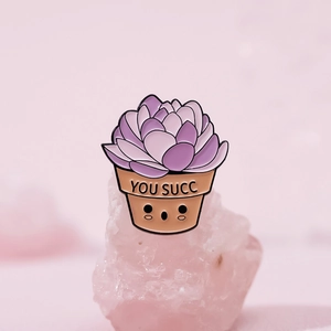 Enamel succulent pin with YOU SUCC pun on light pink crystal base in soft pink lighting