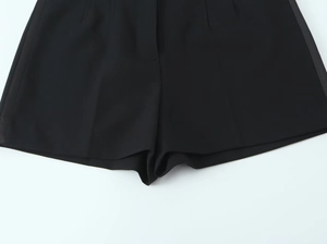 Dettaglio di cuciture pregiate e tessuto nero liscio su pantaloncini da completo