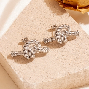 Silver twisted knot stud earrings with sparkling rhinestones on natural stone