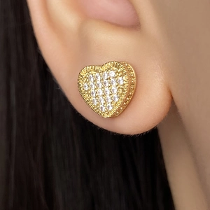 Close-up of a model wearing a gold heart stud earring with micro-pave cubic zirconia