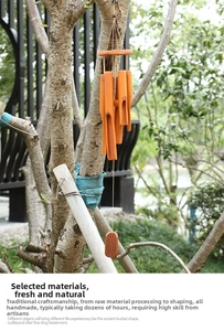 Detailed view of handmade bamboo wind chime tubes hanging from a tree in a natural garden
