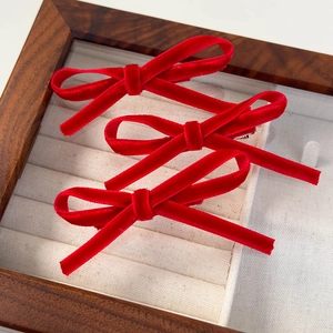 Trois barrettes à nœud en velours rouge présentées dans un coffret à bijoux en bois