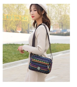 Outdoor shot of a colorful striped canvas crossbody bag with adjustable strap and zippers