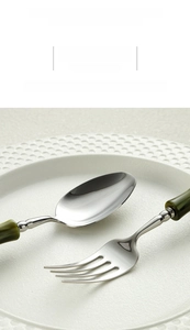 Macro detail of polished stainless steel cutlery with green bamboo style handle