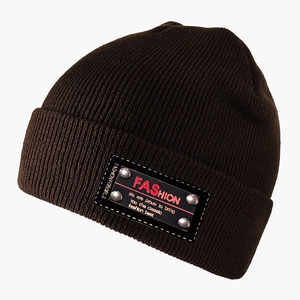 Close-up of a dark brown knit beanie featuring a black patch with silver rivets and red text