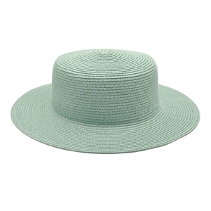 Detailed view of a mint green flat top straw sun hat with fine woven texture and wide brim.