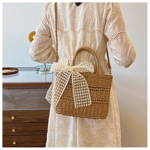 Straw woven tote bag with a large white lace bow shown in a bright interior lifestyle setting