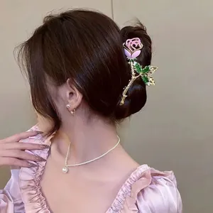 Detailed view of a pink rose hair claw clip with green leaves in a French vintage style