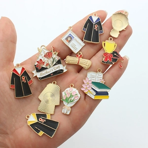 Colorful enamel alloy charms featuring graduation and Mother's Day themes on a hand