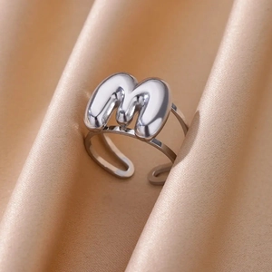 Macro detail of silver bubble letter M ring with adjustable double-row band on silk
