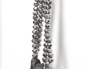 Détail macro de perles facettées gris foncé sur un élégant tissu de robe en satin noir