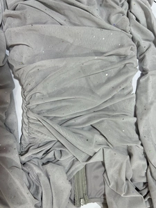 Dettaglio del tessuto a rete grigio con paillettes luccicanti e cerniera a scomparsa
