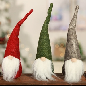 Three Nordic Christmas gnomes in red green and grey felt on a rustic wooden background