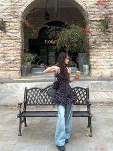 Haut à pois asymétrique porté avec un jean large et un sac à bandoulière noir