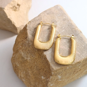 Modern gold-plated U-shaped earrings with vertical textured stripes on natural stone