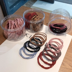 Detailed view of colorful elastic hair ties in transparent storage jars on a wooden table