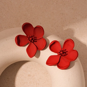 Detailed close-up of matte red flower earrings with 3D stamens on a ceramic display