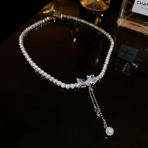Sparkling zircon bow necklace with elegant pearl fringe on black background