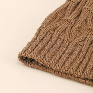 Nahaufnahme der braunen Strickmütze mit Zopfmuster und detaillierter Rippstrick-Textur