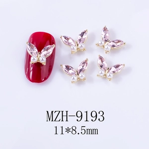 Macro view of butterfly nail jewelry with pink marquise crystals and white pearls
