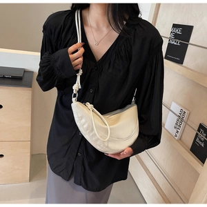 Chic cream dumpling bag with braided strap shown in a professional lifestyle setting