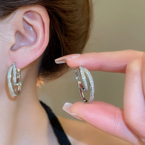 Detail of 18k gold plated U-shaped earrings with zircons on model ear and hand