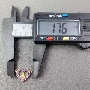 Digital caliper measuring the 17.6mm width of a gold heart pendant with purple gemstone