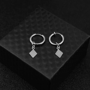 Detail of silver geometric square dangle earrings resting on a black jewelry box
