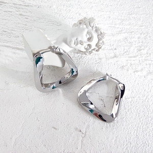 Detailed view of silver irregular triangle earrings with polished finish on white texture
