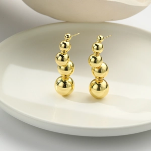 Detail of 18k gold plated ball earrings with five polished beads on a ceramic tray