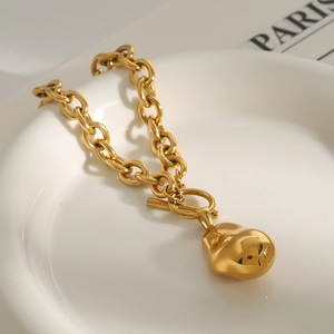 Macro detail of gold-tone chunky chain necklace with waterdrop pendant and OT clasp