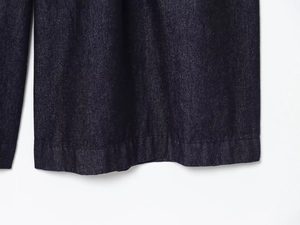 Close-up detail of the hem stitching on dark blue denim high-waisted wide-leg jeans